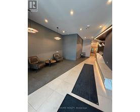 A modern lobby area with a black and white carpet leading to a hallway.