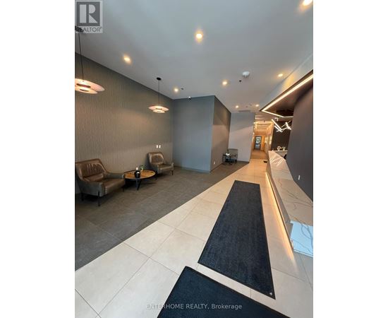 A modern lobby area with a black and white carpet leading to a hallway.