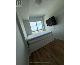 A bedroom with a bed, a window, and a flat screen TV mounted on the wall.