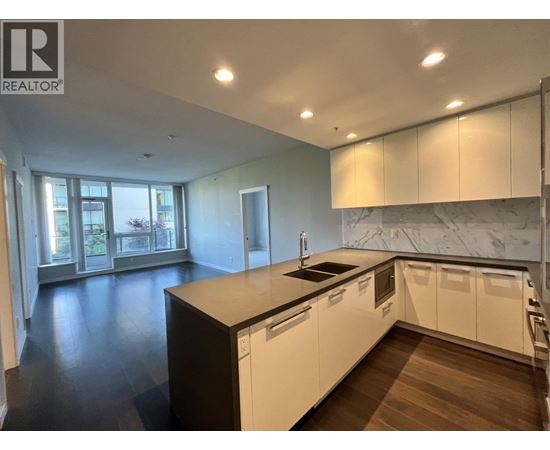 A modern kitchen with white cabinets and a marble backsplash.