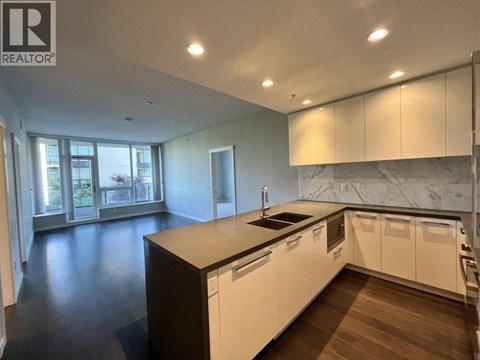 A modern kitchen with white cabinets and a marble backsplash.