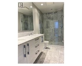 A bathroom with a marble shower and sink.