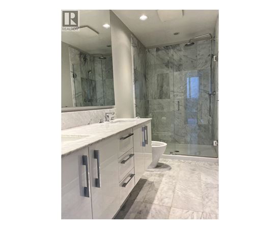 A bathroom with a marble shower and sink.