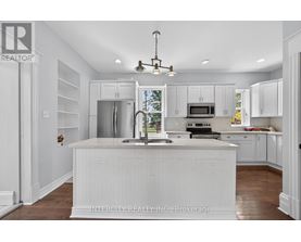 A white kitchen with a sink and a window.