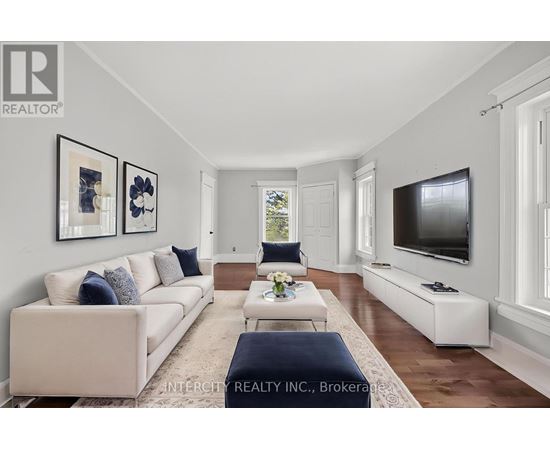 A living room with a white couch and a television on the wall.