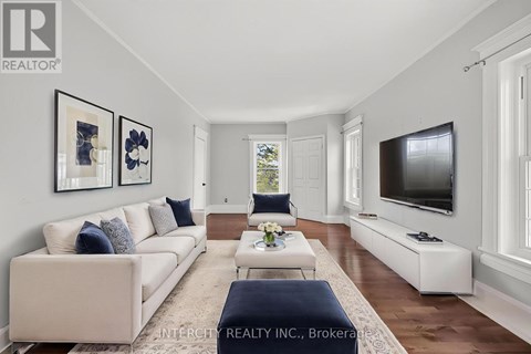 A living room with a white couch and a television on the wall.