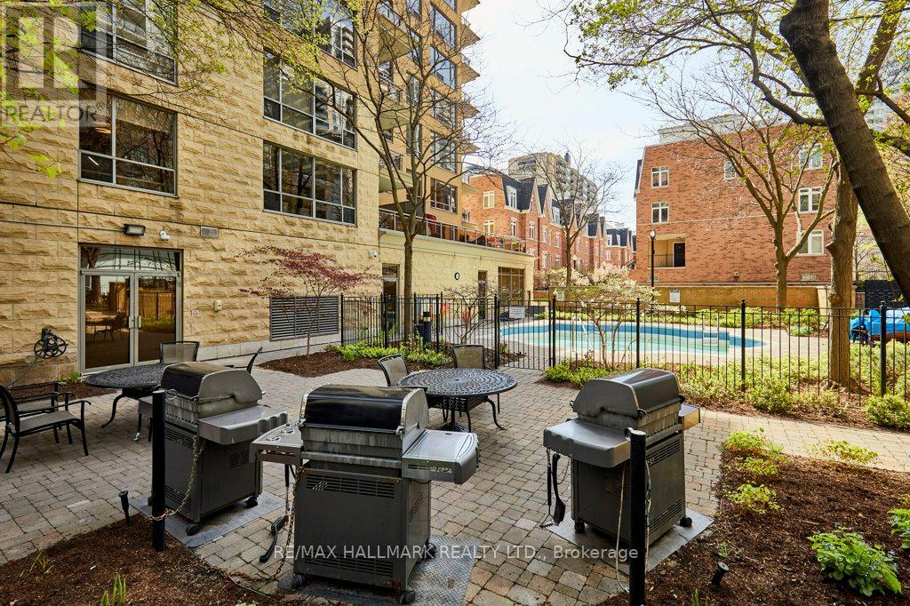 A patio with a grill and a pool in the background.