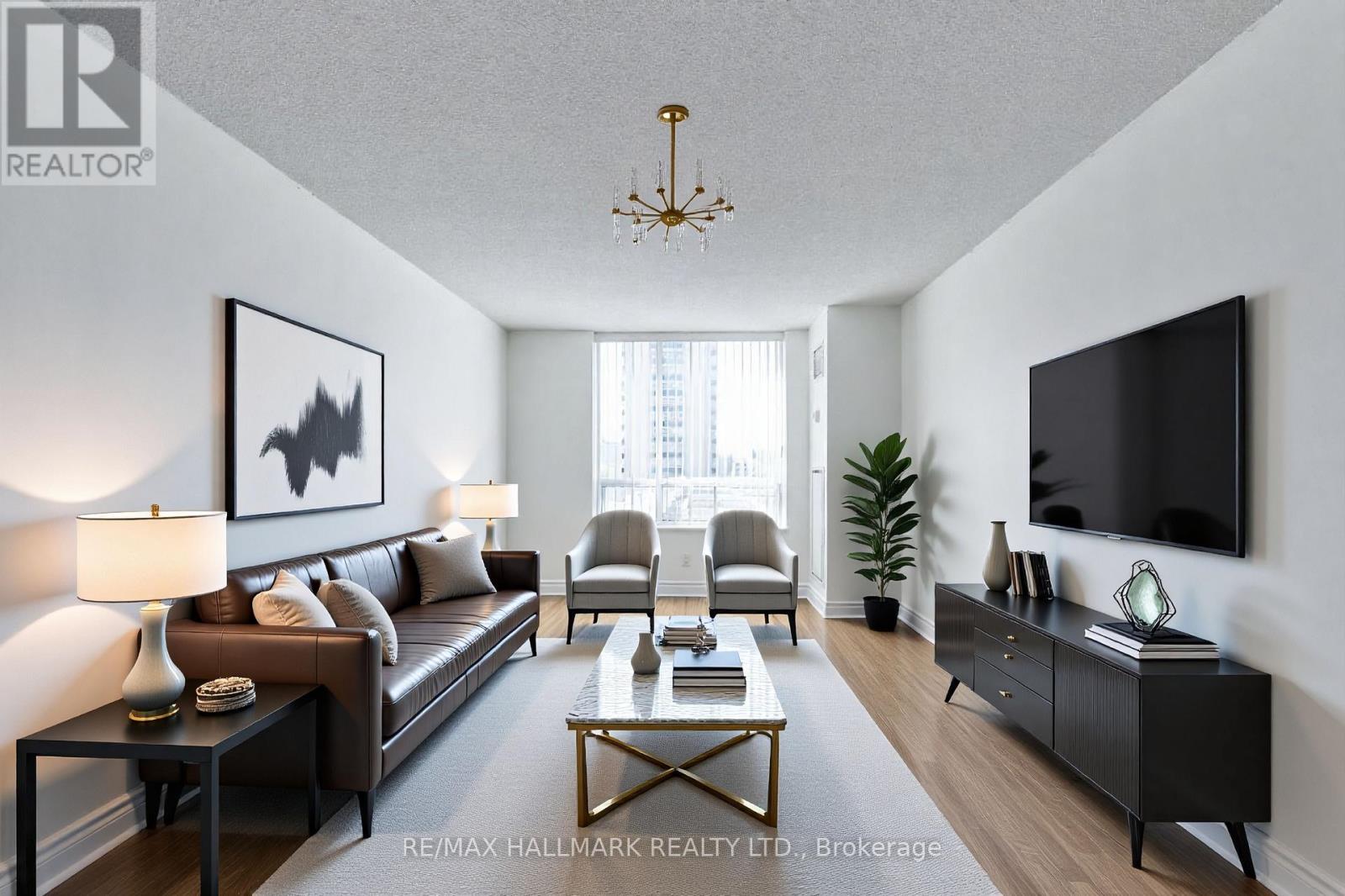 A well-lit living room with a large couch, a coffee table, and a flat-screen TV mounted on the wall.