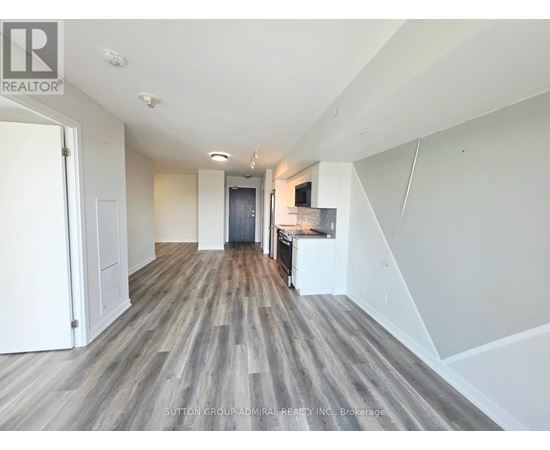 A spacious room with wooden flooring and white walls.