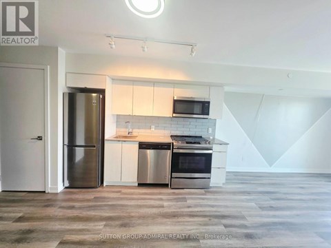 A modern kitchen with a refrigerator, stove, and microwave.
