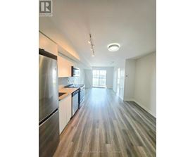 A modern kitchen with wood flooring and stainless steel appliances.
