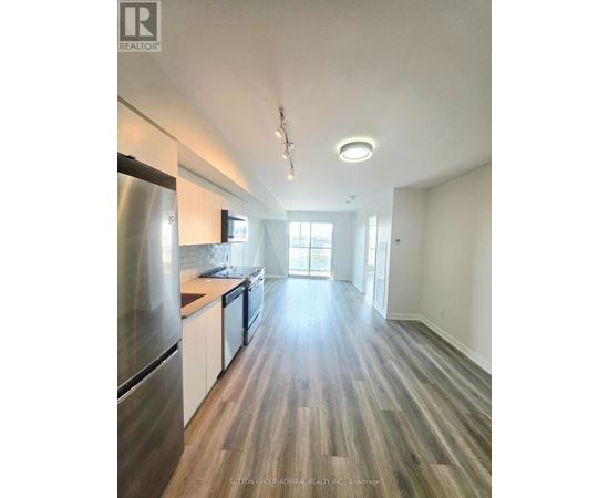 A modern kitchen with wood flooring and stainless steel appliances.