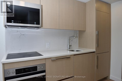 A kitchen with a stove, oven, sink, and cabinets.