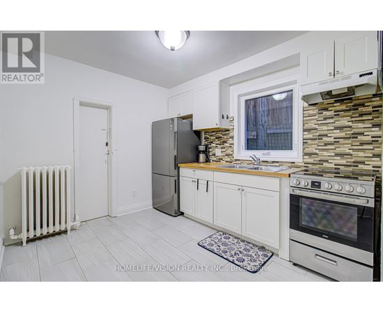A kitchen with white cabinets and a stone backsplash.