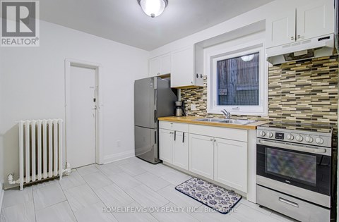 A kitchen with white cabinets and a stone backsplash.