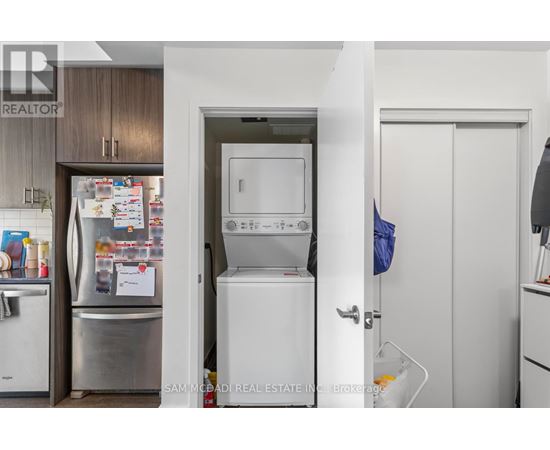 A kitchen with a refrigerator, oven, and a door leading to a laundry room.