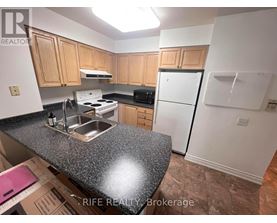 A kitchen with a granite countertop and wooden cabinets.