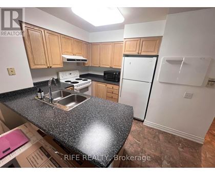 A kitchen with a granite countertop and wooden cabinets.