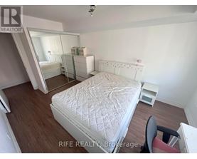 A bedroom with a white bed and a chair.