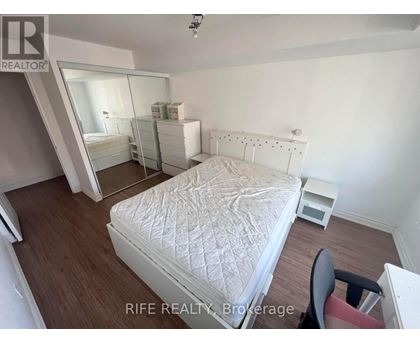 A bedroom with a white bed and a chair.