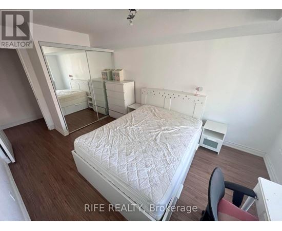 A bedroom with a white bed and a chair.