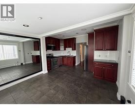 A large, empty kitchen with dark brown cabinets and a tiled floor.