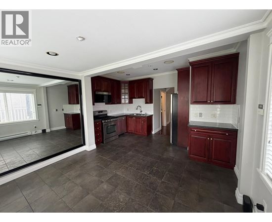 A large, empty kitchen with dark brown cabinets and a tiled floor.