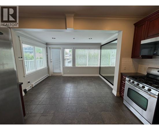 A kitchen with a refrigerator, oven, and microwave.