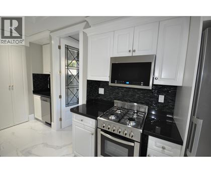 A kitchen with white cabinets and black countertops.