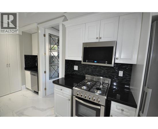 A kitchen with white cabinets and black countertops.