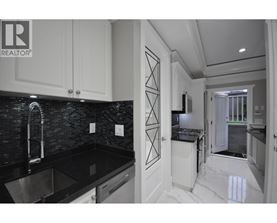A modern kitchen with black countertops and white cabinets.