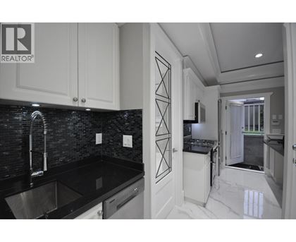 A modern kitchen with black countertops and white cabinets.