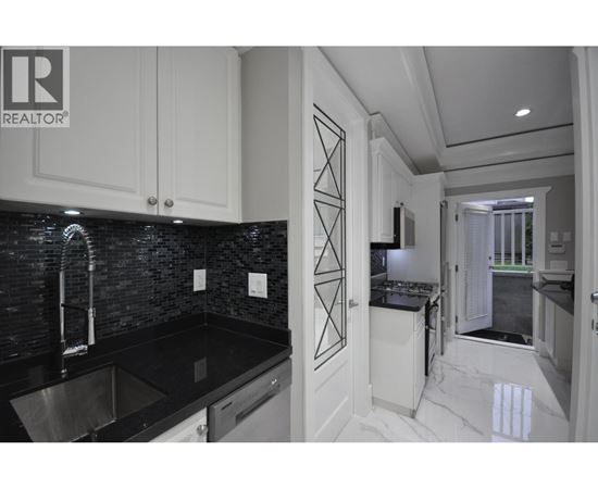 A modern kitchen with black countertops and white cabinets.