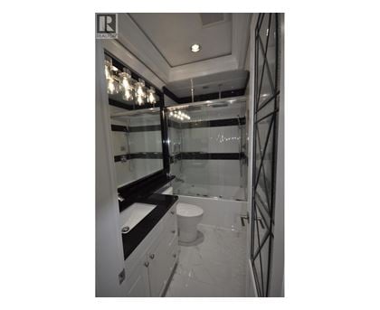 A bathroom with a toilet, sink, and mirror.