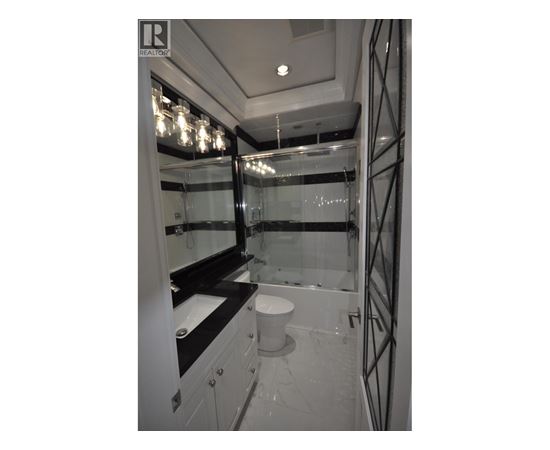 A bathroom with a toilet, sink, and mirror.