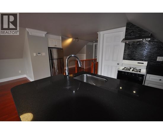 A kitchen with a black counter top and a sink.