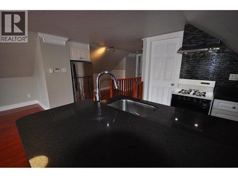 A kitchen with a black counter top and a sink.