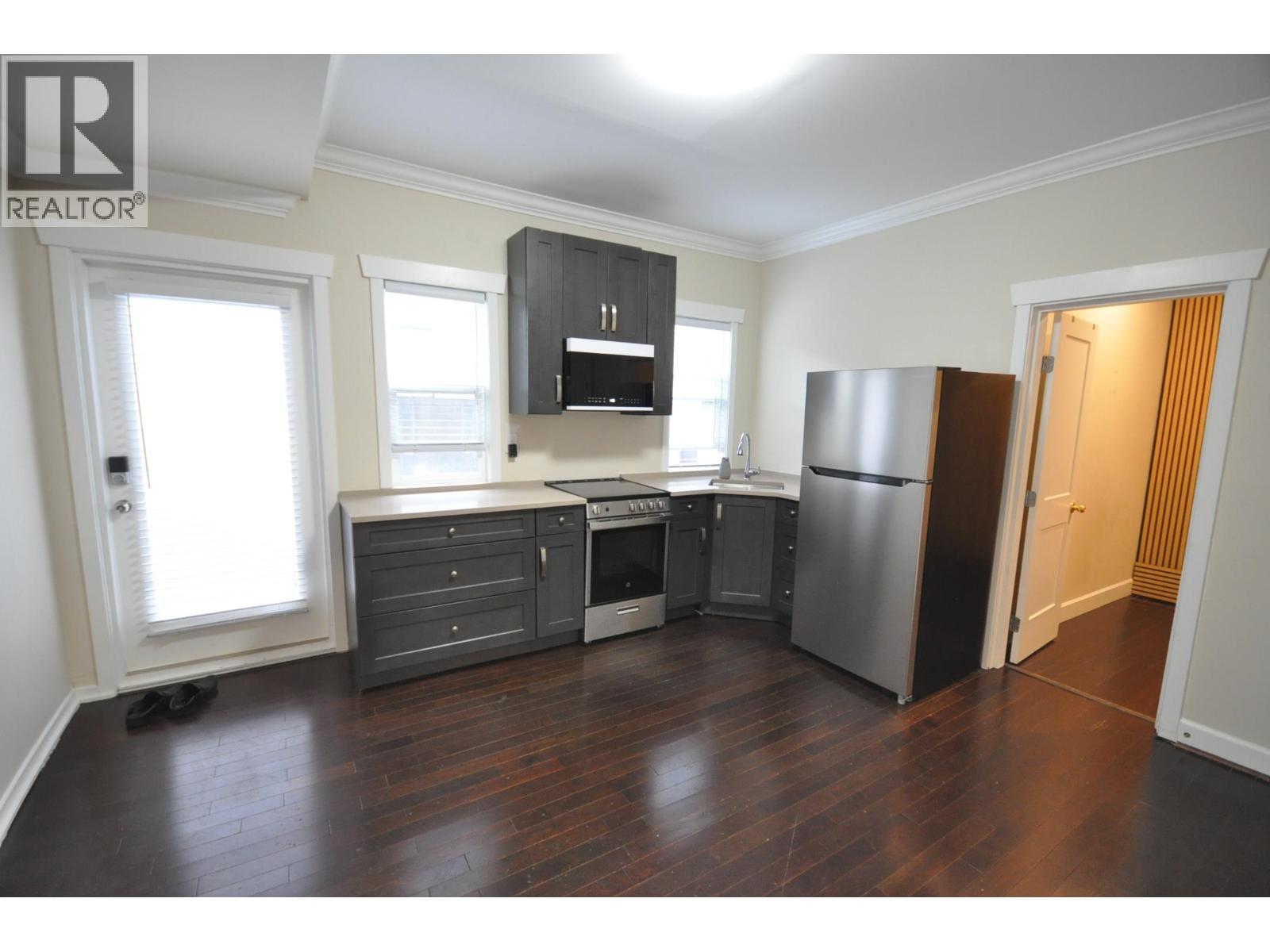 A kitchen with a refrigerator, stove, and cabinets.