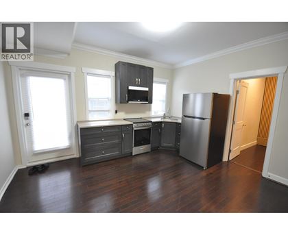A kitchen with a refrigerator, stove, and cabinets.