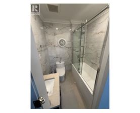 A bathroom with marble walls and a glass shower stall.