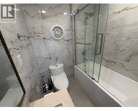A bathroom with marble walls and a glass shower stall.