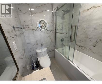 A bathroom with marble walls and a glass shower stall.