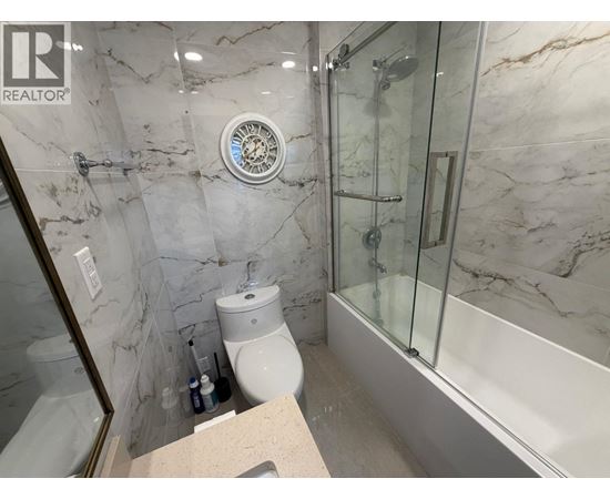 A bathroom with marble walls and a glass shower stall.