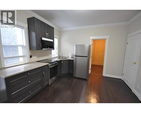 A kitchen with dark wood floors and white walls.