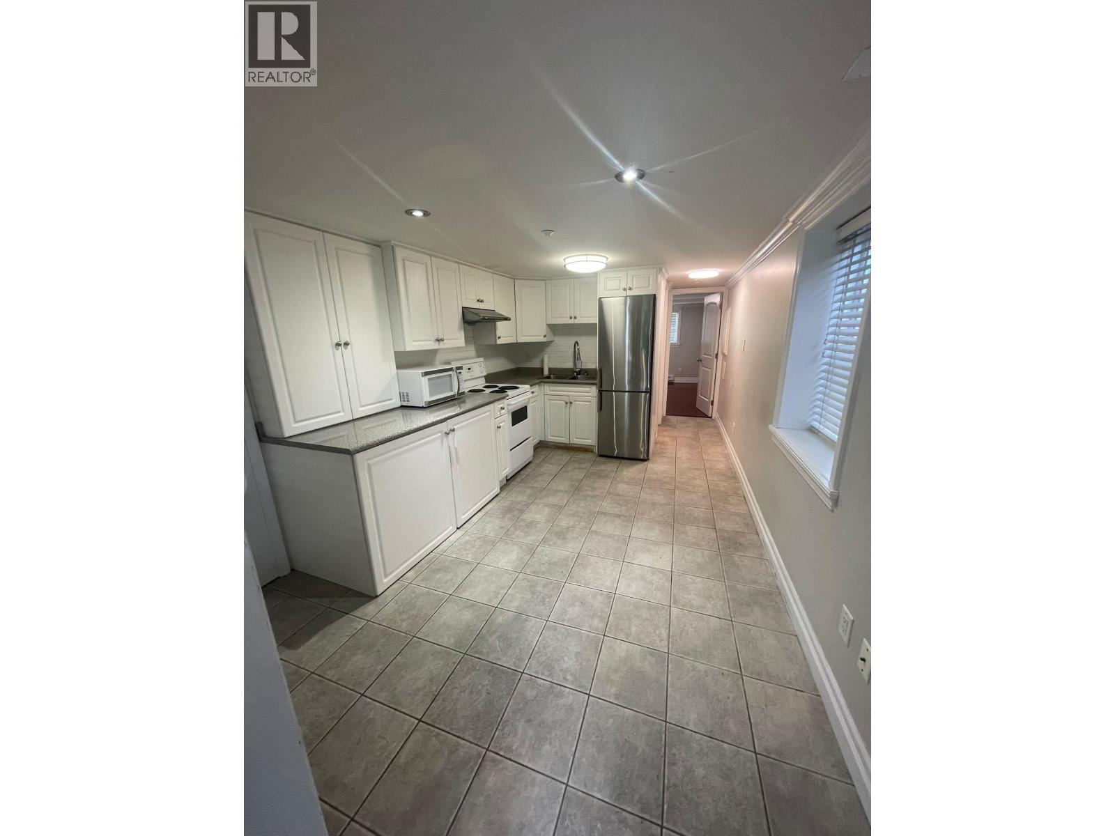 A kitchen with white cabinets and tile flooring.