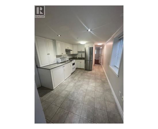 A kitchen with white cabinets and tile flooring.