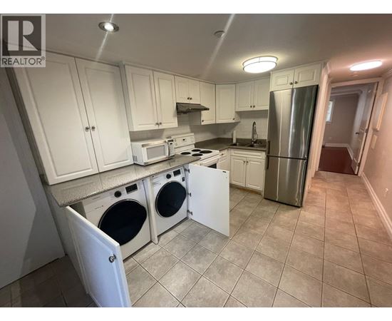 A kitchen with white cabinets and a stainless steel refrigerator.