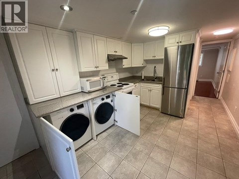 A kitchen with white cabinets and a stainless steel refrigerator.