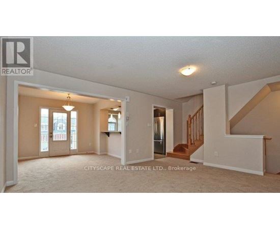A real estate listing photo of a spacious room with a staircase.