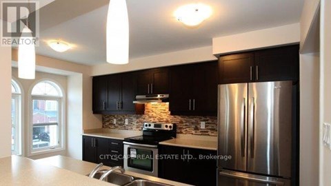 A modern kitchen with a stainless steel refrigerator and black cabinets.